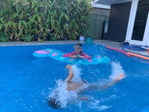 a young girl is in a swimming pool at Woy Woy Staycation - Heated Pool & Hot Tub & BBQ & Pizza Oven & Arcade Game & Pool Table in Woy Woy