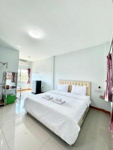 um quarto com uma grande cama branca com lençóis brancos em โรงแรม ปาล์มเพลส em Ban Wang Phai Tha Kham