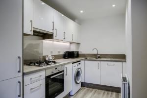 cocina con armarios blancos, lavadora y secadora en Drovers Close, Balsall Common, en Berkswell