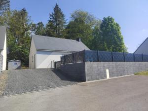 a house with a brick retaining wall and a fence at L'Océraline - Maison avec jardin et wifi in La Lucerne-dʼOutremer