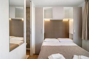 a small bedroom with two beds and a mirror at New Generation La pineta 7 in Albenga +23 photos