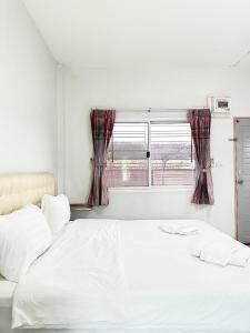 1 dormitorio con cama blanca y ventana en โรงแรม ปาล์มเพลส en Ban Wang Phai Tha Kham