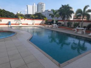 a swimming pool with chairs and a table in a building at Flat Aconchegante in Campos dos Goytacazes