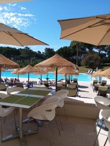 un tavolo con sedie e ombrelloni accanto alla piscina di Quinta do Lago Villa and Golf a Quinta do Lago