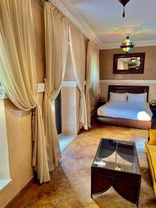 um quarto com uma cama com cortinas e uma mesa de centro em Riad Ta'achchaqa em Marrakech