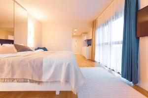 a bedroom with a white bed and a large window at Orbi City Lux in Batumi