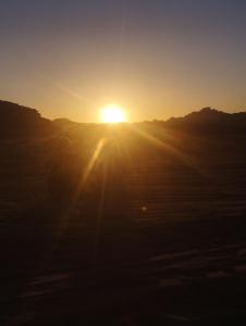 a person is standing in front of the sunset at Waid Rum Jordan Jordan in Wadi Rum