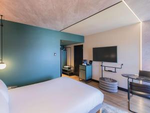 - une chambre avec un grand lit et un mur bleu dans l'établissement Novotel Lisboa, à Lisbonne