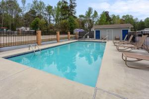 a swimming pool with chairs and a fence at Days Inn by Wyndham Douglasville-Atlanta-Fairburn Road in Douglasville