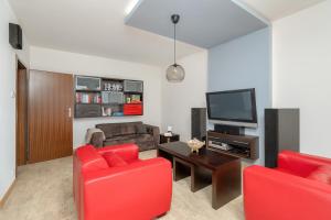 een woonkamer met rode stoelen en een flatscreen-tv bij Apartament nad Wartą z Parkingiem w Poznaniu by Renters in Poznań