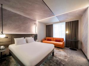 um quarto de hotel com uma cama grande e um sofá laranja em Novotel Praha Wenceslas Square em Praga