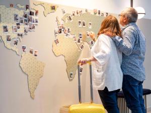 una coppia anziana che sta davanti a una mappa del mondo di Aparthotel Adagio Paris Centre Tour Eiffel a Parigi