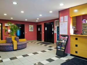 um lobby com paredes e cadeiras vermelhas e uma farmácia em Aparthotel Adagio Access Paris Maisons-Alfort em Maisons-Alfort
