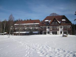 a building in the snow with footprints in the snow at Ferienclub Erlenbruck in Hinterzarten