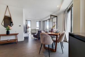 une chambre avec une table et des chaises ainsi qu'un salon dans l'établissement Three Bed Serviced Apartment by London ExCeL, à Londres