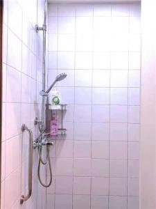 een wit betegelde badkamer met een douche met een douchekop bij Xi'an Xianyang International Airport Space Capsule Hotel in Xi'an