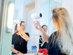 a woman blow drying her hair in front of a mirror at ibis budget Sao Paulo Jardins in Sao Paulo