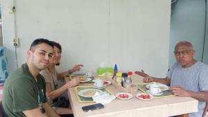 un grupo de personas sentadas en una mesa comiendo comida en Renata Cottages, en Ohoililir