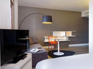 a room with a bed and a table and a tv at Novotel Suites Perpignan Centre in Perpignan