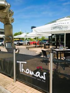 a sign for a restaurant with tables and umbrellas at Future Inn Cardiff Bay in Cardiff