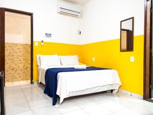 1 dormitorio con 2 camas y pared amarilla en Pousada Sol e Mar, en Morro de São Paulo