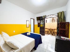 a bedroom with a bed and a yellow wall at Pousada Sol e Mar in Morro de São Paulo