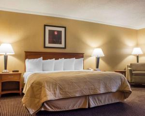 a hotel room with a bed and a chair at Clarion Hotel & Suites Riverfront in Oswego