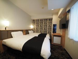 鹿児島市にあるアパホテル 鹿児島中央駅前 のベッドとテレビが備わるホテルルームです。