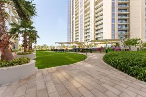 une passerelle dans un parc planté de palmiers et de bâtiments dans l'établissement Maison Privee - City Chic Retreat in Dubai Prime Location, à Dubaï