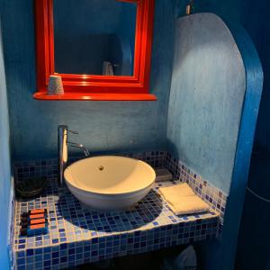 bagno blu con lavandino e specchio di Mediterraneo Hotel a Meyisti