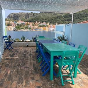 Mediterraneo Hotel في ماغيستي: طاولة خضراء وكراسي على فناء مطل على الماء