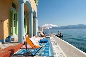 a row of chairs and umbrellas on a dock with the water at Mediterraneo Hotel in Meyisti