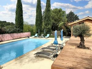 una piscina con sedie a sdraio e ombrelloni blu di Maison de 3 chambres avec piscine partagee jardin clos et wifi a Saint Andre de Cruzieres a Saint-André-de-Cruzières