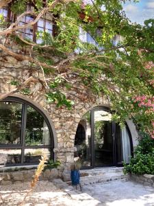 un edificio in pietra con finestre e un albero di Maison de 3 chambres avec piscine partagee jardin clos et wifi a Saint Andre de Cruzieres a Saint-André-de-Cruzières