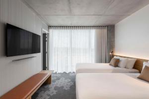 a hotel room with two beds and a flat screen tv at Vibe Hotel Adelaide in Adelaide