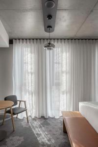 a bedroom with white curtains and a bed and a table at Vibe Hotel Adelaide in Adelaide