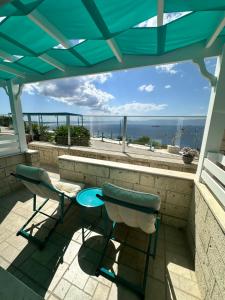 eine Terrasse mit 2 Stühlen und einem Tisch sowie Meerblick in der Unterkunft Fener Hotel Café & Kahvalti in Cesme