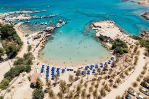 a beach with umbrellas and people in the water at Green Bay Suites in Protaras
