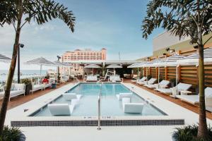 una piscina en la azotea de un hotel con sillones blancos en The Hiatus Clearwater Beach, Curio Collection By Hilton, en Clearwater Beach