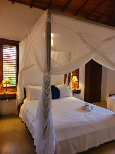 a bedroom with a white bed with a canopy at Guest House Villa 2 Santos in Arraial d'Ajuda +59 photos