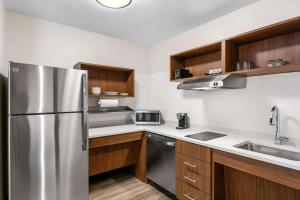 a kitchen with a stainless steel refrigerator and wooden cabinets at Everhome Suites Lexington North in Lexington