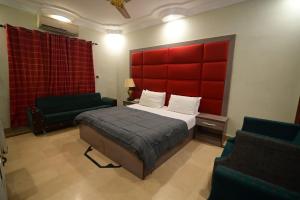 a bedroom with a bed with a red headboard and two chairs at SEAVIEW COTTAGE in Karachi