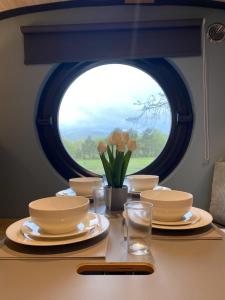 uma mesa com pratos e copos e uma janela em Celtic Minor Pods em Ystalyfera