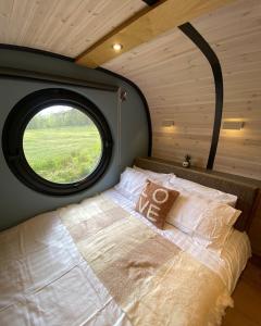 Bett in einem Zimmer mit rundem Fenster in der Unterkunft Celtic Minor Pods in Ystalyfera