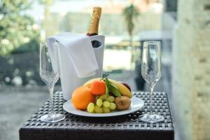 a plate of fruit on a table with wine glasses at Avala Resort & Villas in Budva