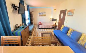 a living room with a blue couch and a bedroom at Maison de la Lagune in Oualidia