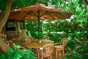 een houten tafel en stoelen onder een paraplu bij Desert Rose Resort Kisumu in Kisumu