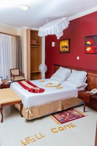 1 dormitorio con 1 cama grande y pared roja en Desert Rose Resort Kisumu en Kisumu