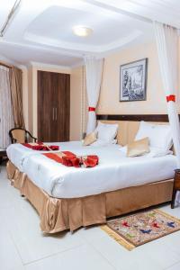 a bedroom with a large bed with red sheets at Desert Rose Resort Kisumu in Kisumu