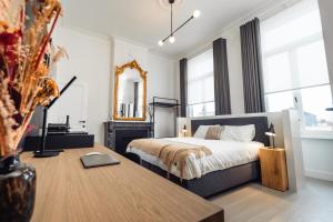 1 dormitorio con cama, mesa y espejo en Luxeverblijf B&B het Wevershuis, en Herentals